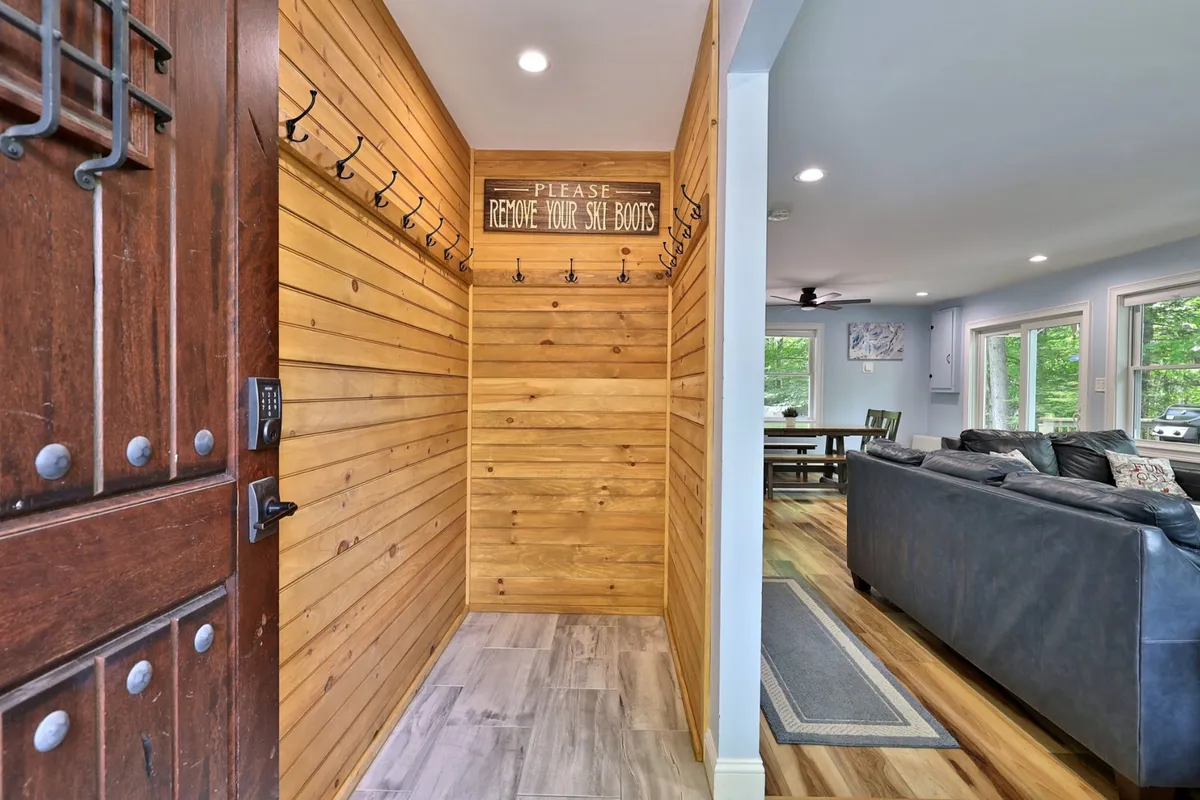 An inviting mudroom interior with wooden wall paneling, coat hooks, and a welcome sign. This space is practical, warm, and tailored for organizing outdoor gear after a day on the mountain.