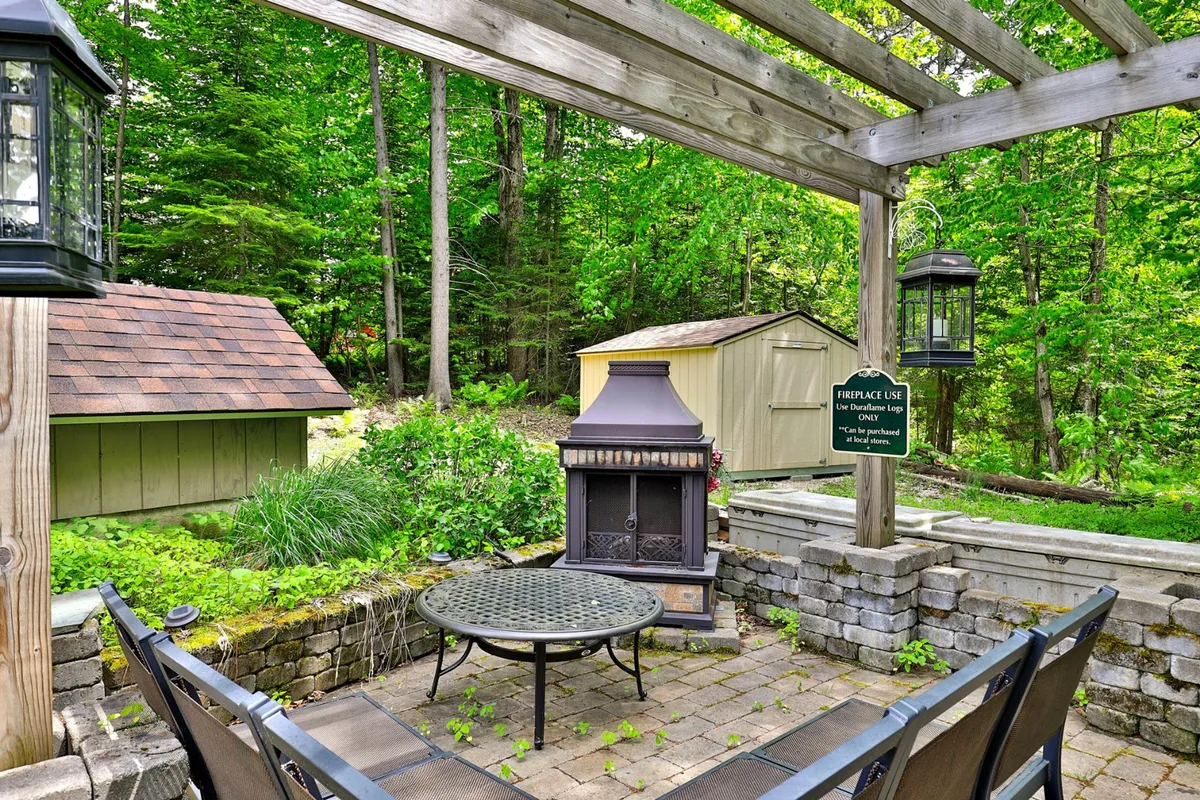 This image showcases an inviting outdoor dining area with a table and chairs set near an outdoor fireplace, surrounded by lush greenery—a perfect spot for socializing, relaxing, or enjoying a meal al fresco after exploring local nightlife.