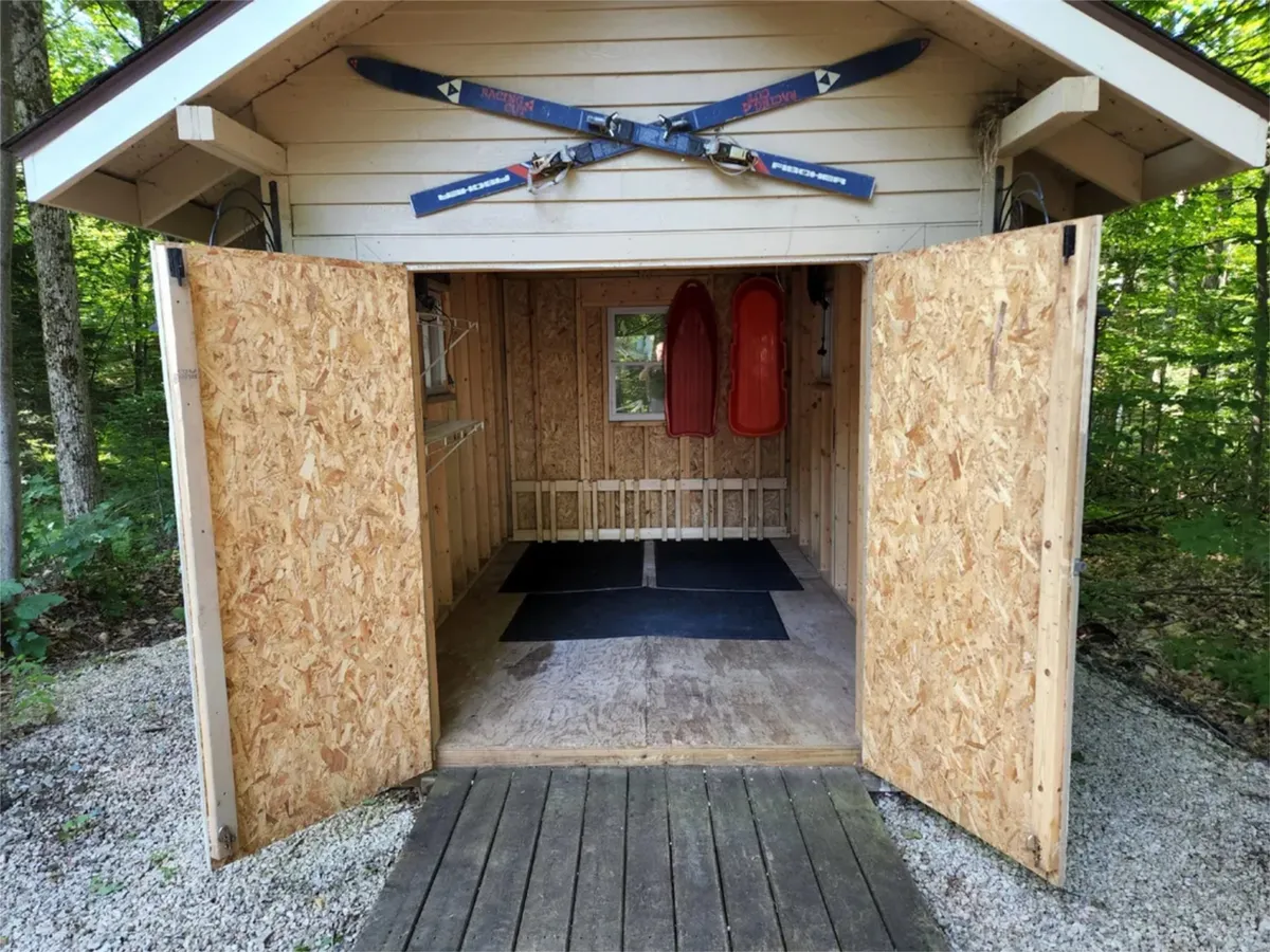This image captures the ski equipment mounted on the wall and red sleds resting nearby, with open doors hinting at easy access. The practical and playful setup evokes excitement for winter sports and readiness for adventure.