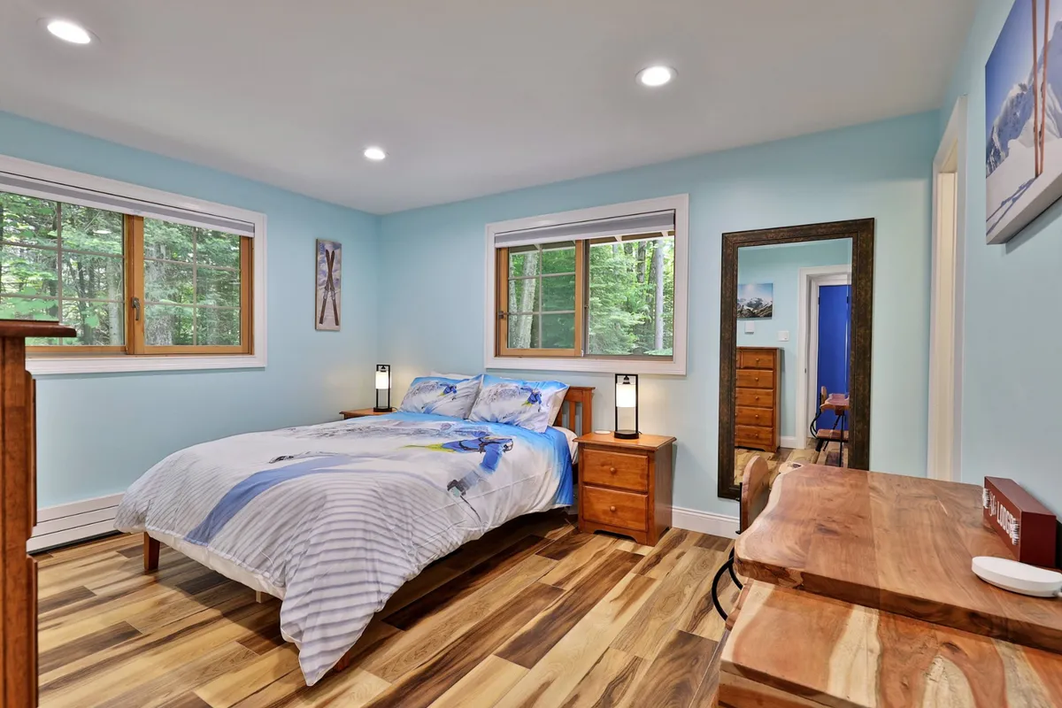 This image showcases a peaceful bedroom featuring a large bed, multiple windows letting in natural light, and dressers for storage. The room feels calm and inviting, perfect for rest and relaxation after a long day.